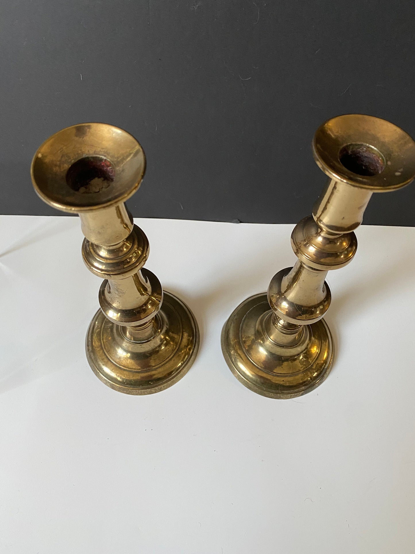 A  Pair antique brass candlesticks with pushers   Small dent at the bottom of one  Totally useable  9 inches tall